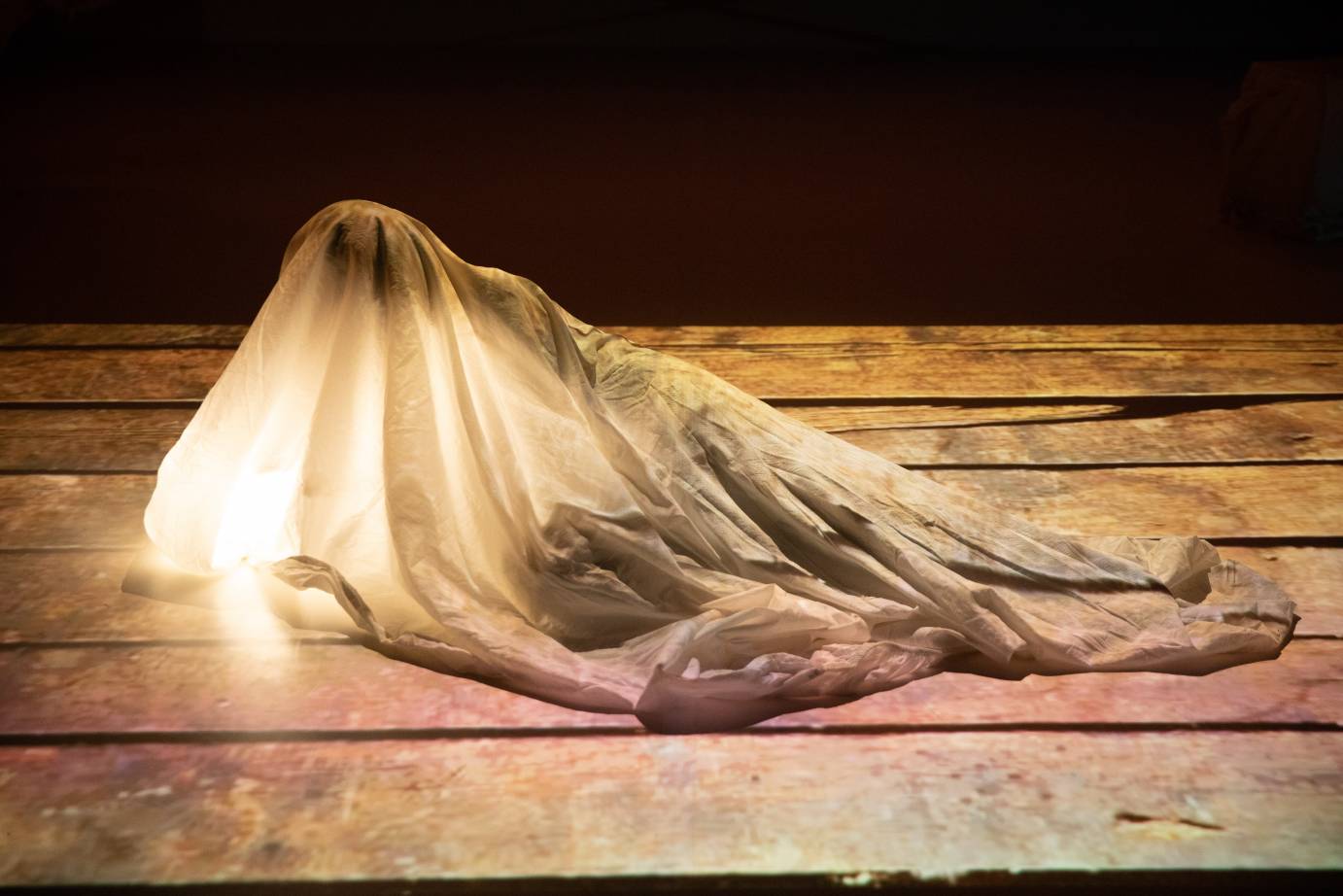 A woman lies in a white shroud